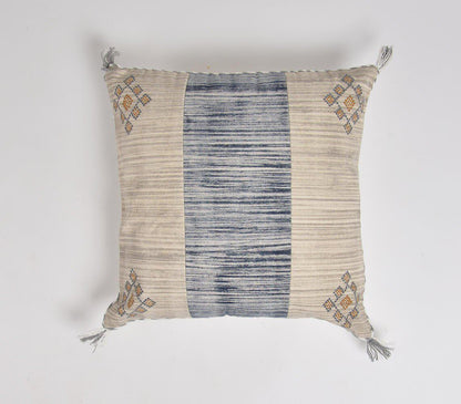 Square cushion cover with beige and blue striped pattern, featuring embroidered geometric designs in corners and decorative tassels. Handcrafted coastal-inspired textile with a blend of traditional and contemporary style.